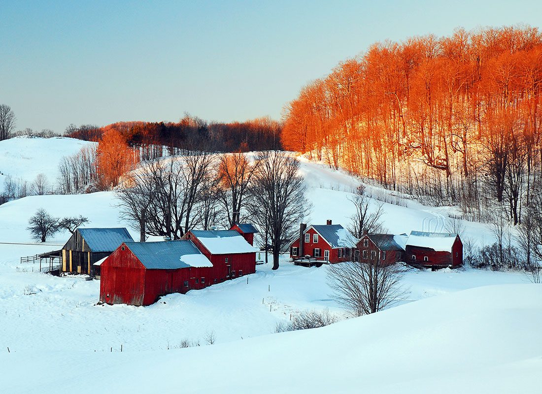 Insurance Solutions - New England Farm on a Snowy Day With Fall Trees in the Background