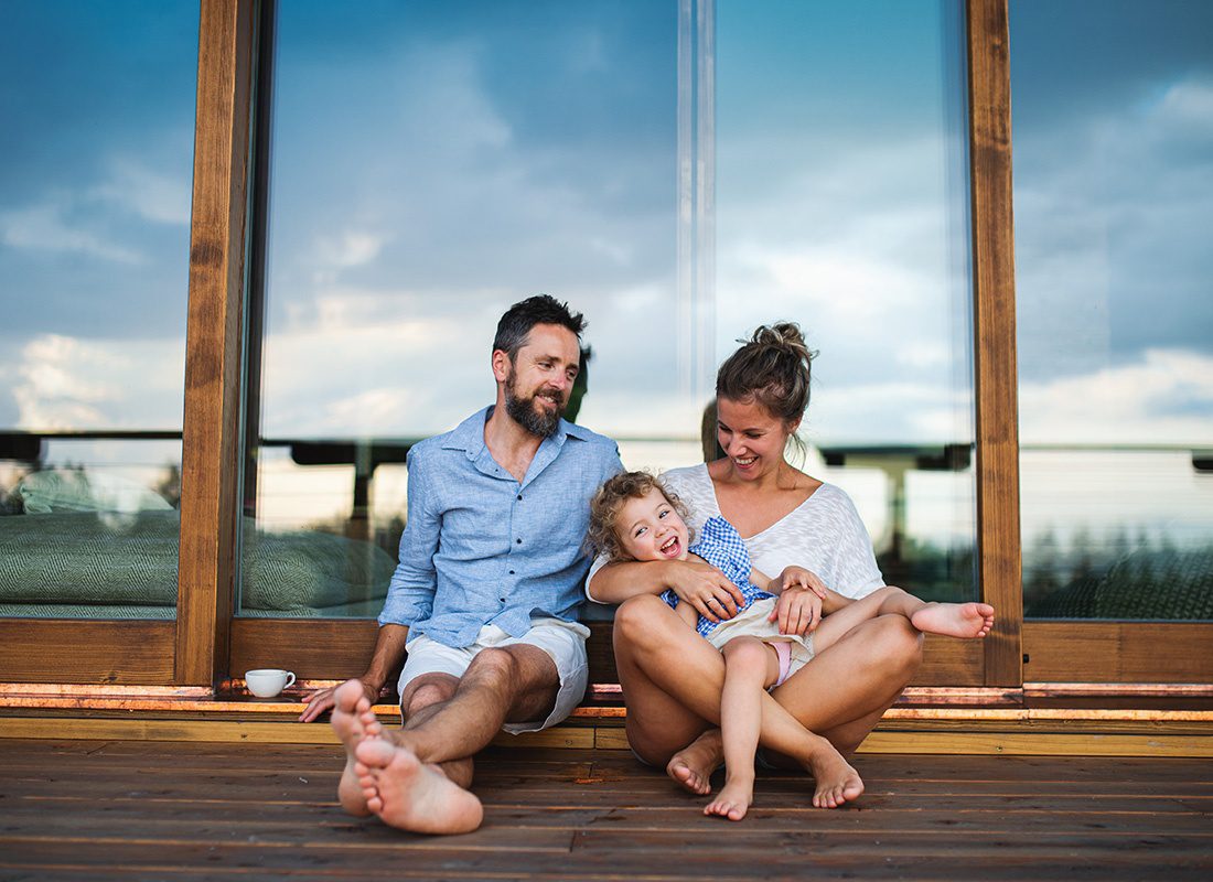 Personal Insurance - Family With Small Daughter Sitting on Patio of Wooden Cabin